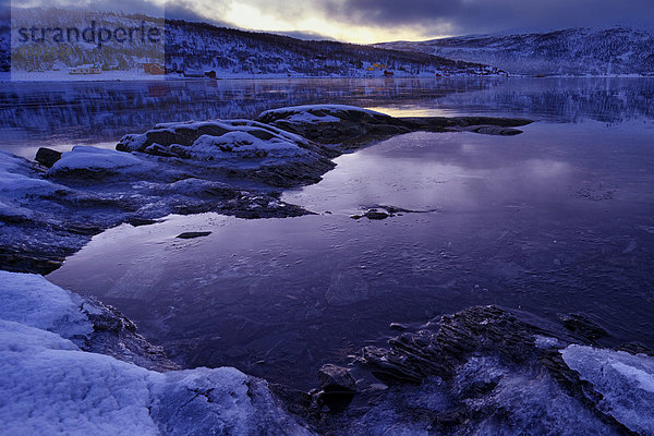 Fjord mit eisbedecktem Ufer im Abendlicht