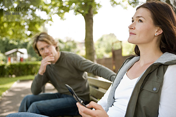 Eine junge Frau und ein junger Mann flirten im Park