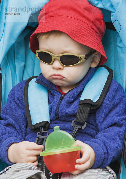 sitzend Portrait Junge - Person Hut Kinderwagen rot jung Respektlosigkeit Kleidung Verbindung sehen Sonnenbrille