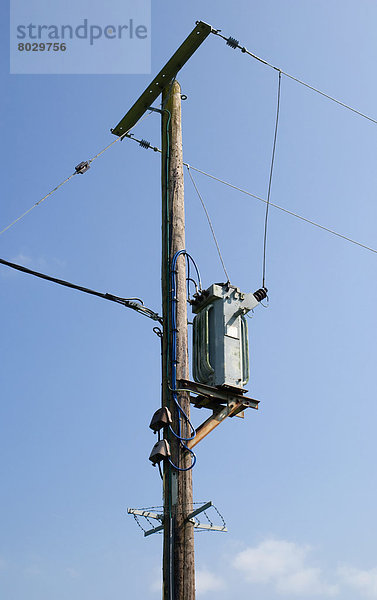 Telefon und Strom Kabel und Post gegen einen blauen Himmel  England