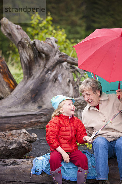 Vereinigte Staaten von Amerika  USA  sitzend  Tag  Spiel  Strand  Sommer  Regenschirm  Schirm  Regen  Enkeltochter  Großmutter  zeigen  Sonnenschirm  Schirm