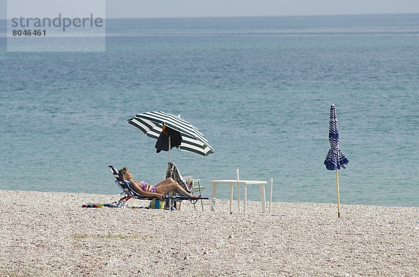 Frau  Stuhl  Strand  Regenschirm  Schirm  sonnenbaden  sonnen  Kieselstein  Faulheit  faul  faule  faulen  fauler  faules  Sonnenschirm  Schirm  Italien  Marken  Sonne