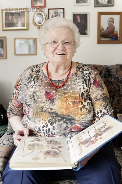 Lächelnde alte Frau mit Pflanzen-Album