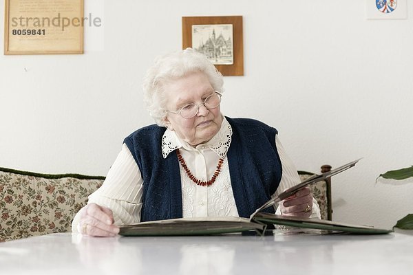 Alte Frau schaut in ein Fotoalbum