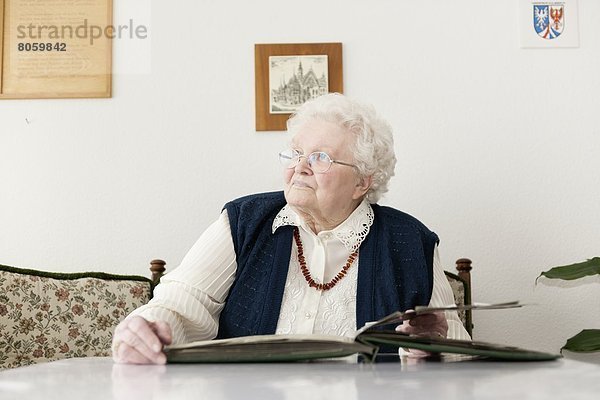 Alte Frau schaut mit einem Fotoalbum