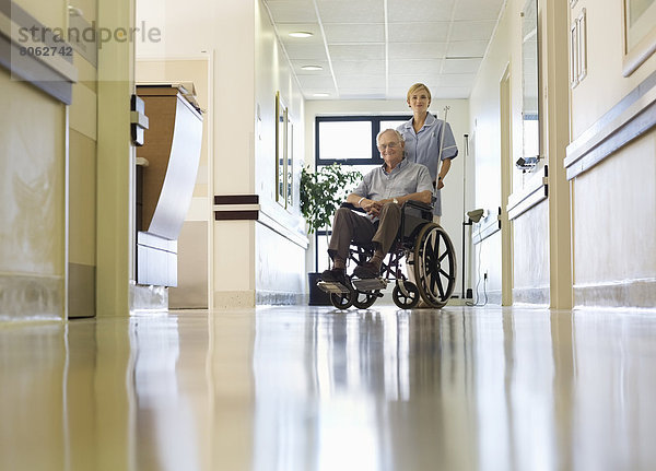 Krankenschwester  die einen älteren Patienten ins Krankenhaus bringt.