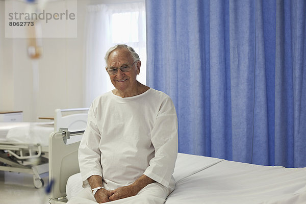 Älterer Patient sitzt auf dem Krankenhausbett