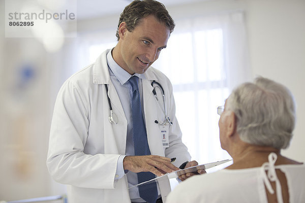 Arzt im Gespräch mit älteren Patienten im Krankenhaus