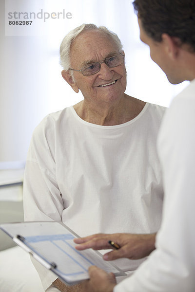 Arzt im Gespräch mit älteren Patienten im Krankenhauszimmer