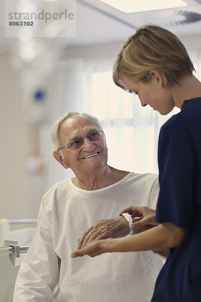 Krankenschwester liest medizinisches Armband eines älteren Patienten im Krankenhaus