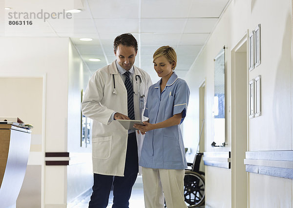 Arzt und Krankenschwester mit Tablet-Computer im Krankenhausflur