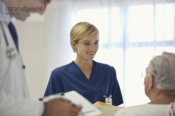 Arzt und Krankenschwester im Gespräch mit älteren Patienten im Krankenhauszimmer