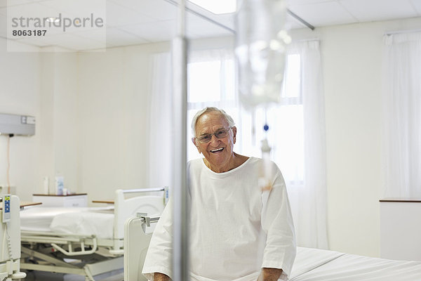 Älterer Patient im Krankenhauszimmer auf dem Bett sitzend