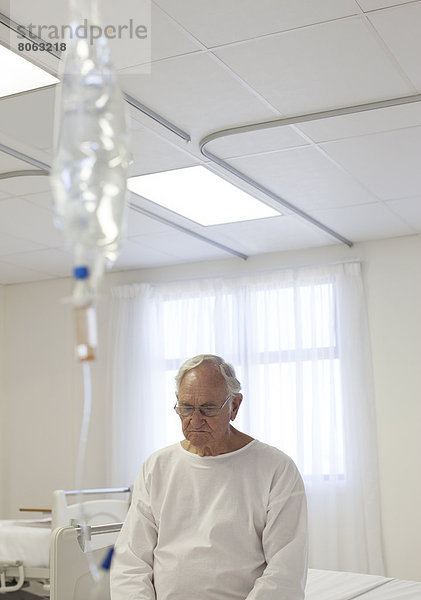 Älterer Patient im Krankenhauszimmer auf dem Bett sitzend