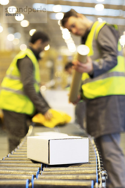 Mitarbeiter prüfen Pakete auf dem Transportband im Lager