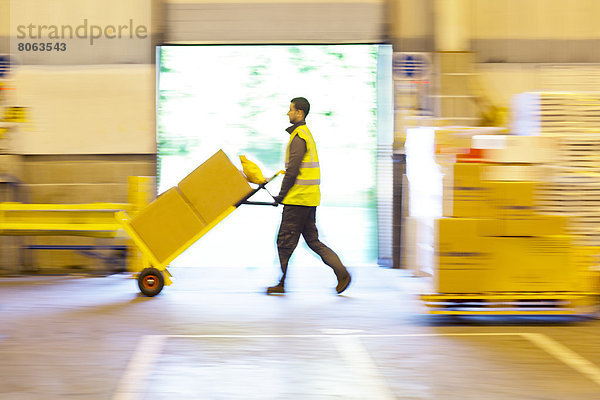 Verschwommene Ansicht des Arbeiters  der die Kisten im Lager schiebt.