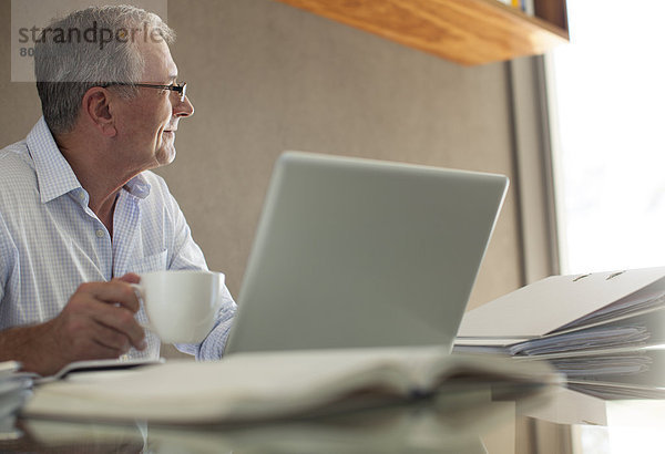 Geschäftsmann bei einer Tasse Kaffee am Laptop