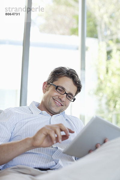 Mann mit Tablet-Computer auf dem Sofa