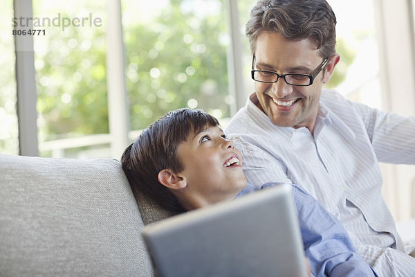 Vater und Sohn mit Tablet-Computer auf dem Sofa