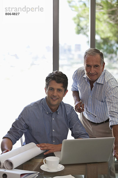 Älterer Mann und jüngerer Mann bei der Arbeit am Schreibtisch