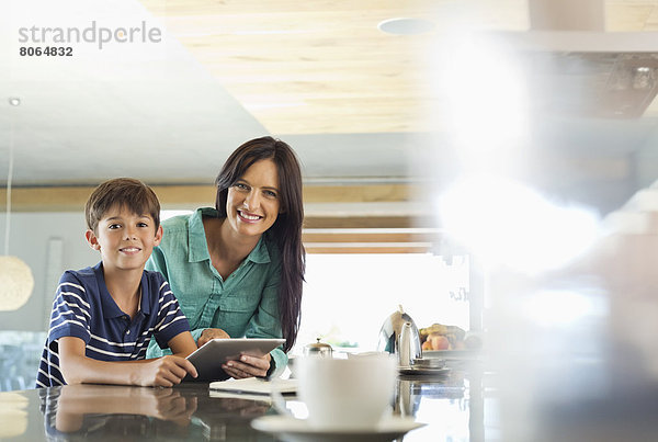 Mutter und Sohn mit Tablet-Computer in der Küche
