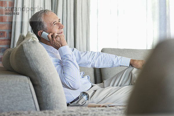 Älterer Mann beim Telefonieren auf dem Sofa