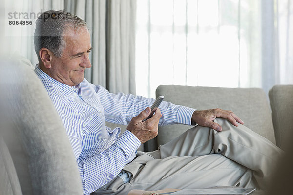 Älterer Mann mit Handy auf dem Sofa