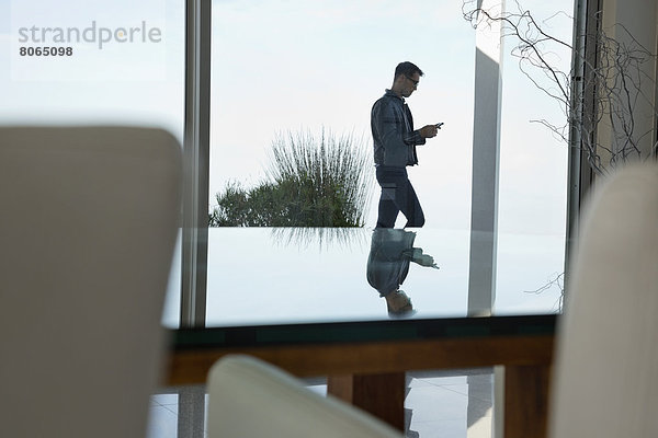 Geschäftsmann mit Handy am Bürofenster