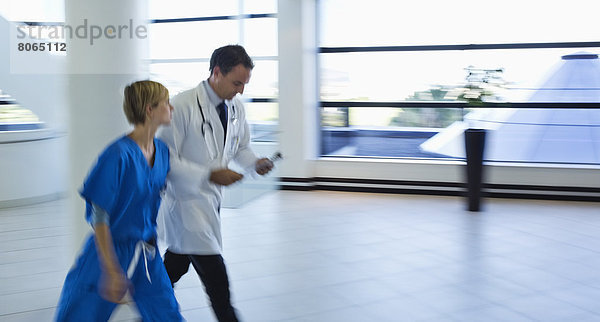 Arzt und Krankenschwester sprechen im Krankenhausflur
