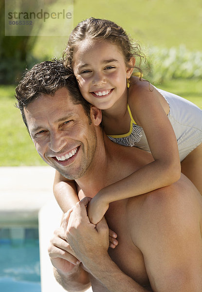 Vater und Tochter lächeln am Swimmingpool