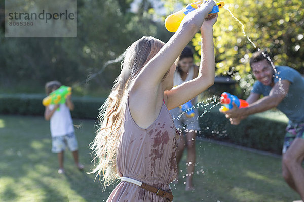 Familienspiel mit Wasserpistolen im Hinterhof