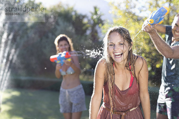Freunde spielen mit Wasserpistolen im Hinterhof