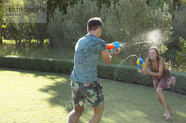 Pärchen spielen mit Wasserpistolen im Garten