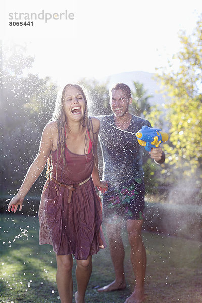 Pärchen spielen mit Wasserpistolen im Garten