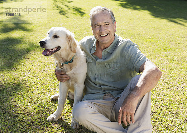 Älterer Mann umarmt Hund im Hinterhof