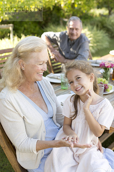 Ältere Frau sitzend mit Enkelin im Freien