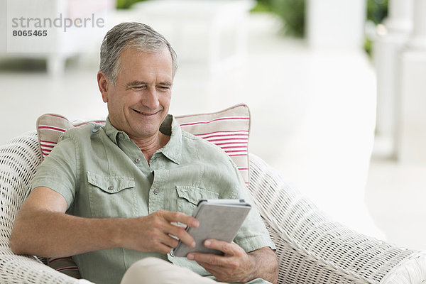 Älterer Mann mit Tablet-Computer auf der Veranda