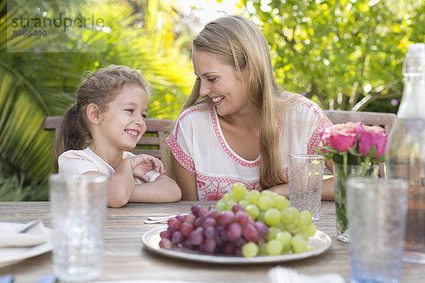 Mutter und Tochter lächeln bei Tisch im Freien