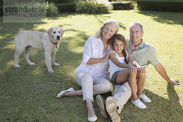 Älteres Paar lächelt mit Enkelin im Hinterhof