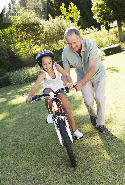 Älterer Mann lehrt Enkelin Fahrrad fahren
