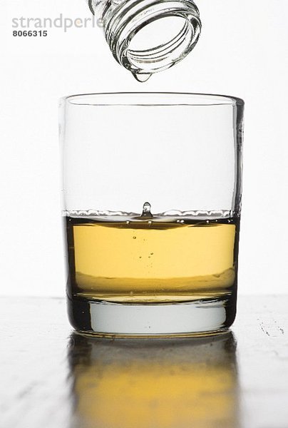 Letzter Tropfen Whiskey tropft aus Flasche in Glas