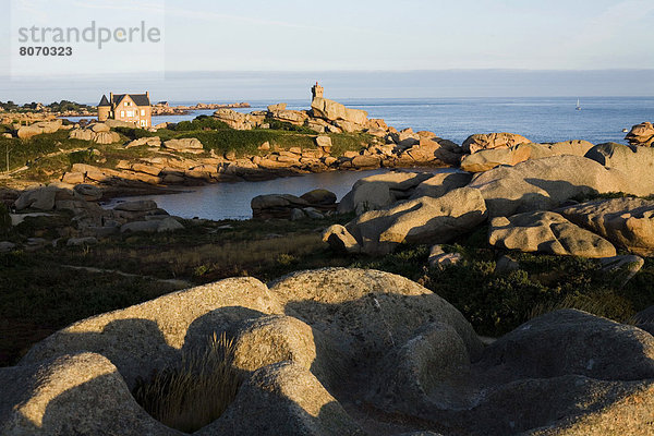 hinter Felsbrocken Mann verstecken Wohnhaus Küste Leuchtturm pink Cote de Granit Rose Granit Ploumanach