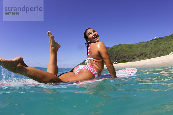 hoch oben liegend liegen liegt liegendes liegender liegende daliegen junge Frau junge Frauen lächeln halten Surfboard