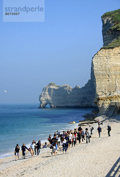 Fröhlichkeit  Strand  Steilküste  Tourist  Kieselstein  Eingang  Menschen im Hintergrund  Hintergrundperson  Hintergrundpersonen  Sonne