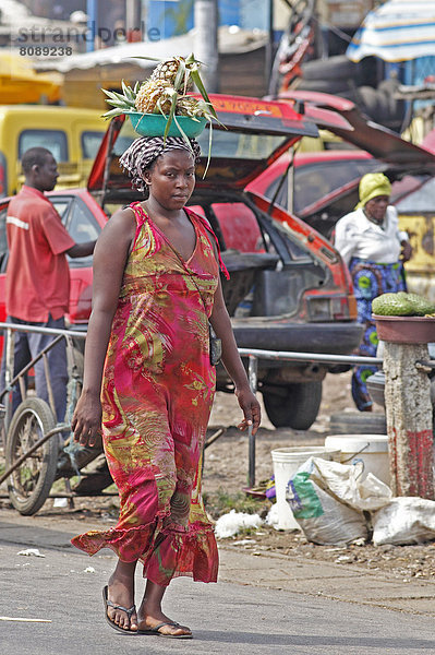 Marktfrau trägt Ananas auf dem Kopf