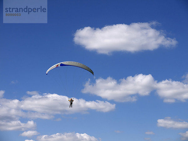 Paragliding am sommerlichen Wolkenhimmel