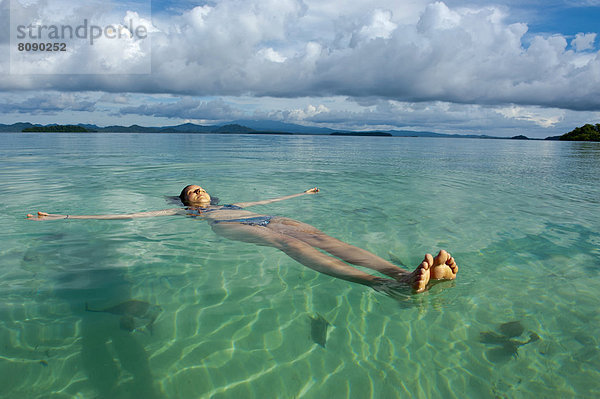 Eine Touristin lässt sich im klaren Wasser der Marovo Lagune treiben