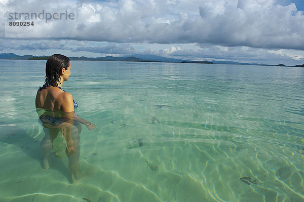 Eine Touristin steht im klaren Wasser der Marovo Lagune