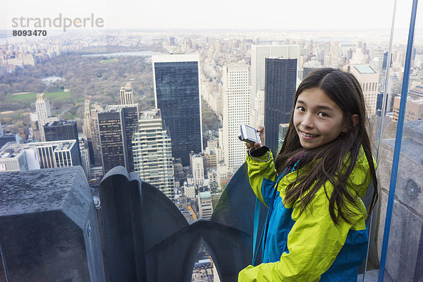 Mixed race girl taking pictures from rooftop  New York City  New York  United States