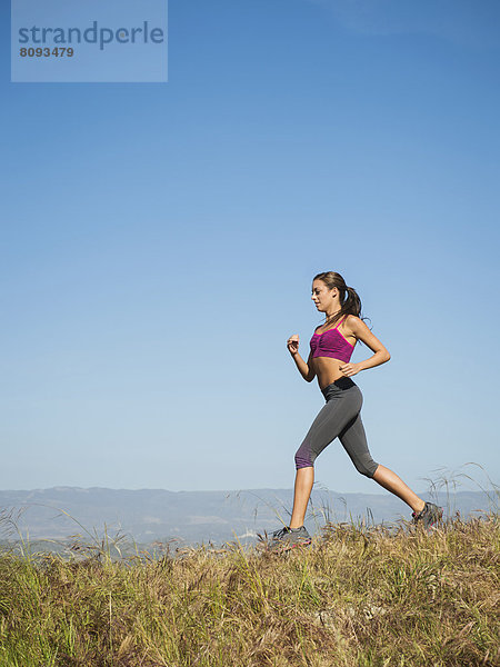 Mixed race woman running in rural landscape